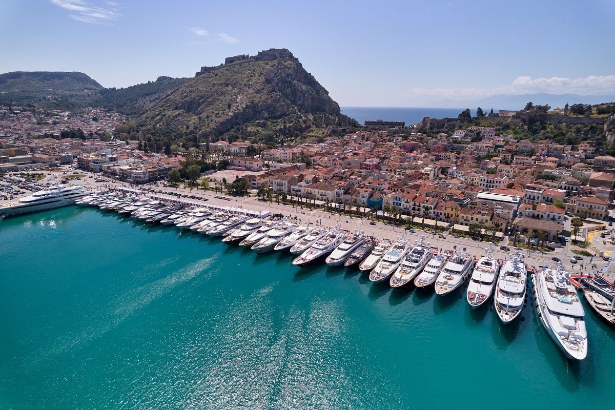 A yacht sailing on blue water near a coastal town